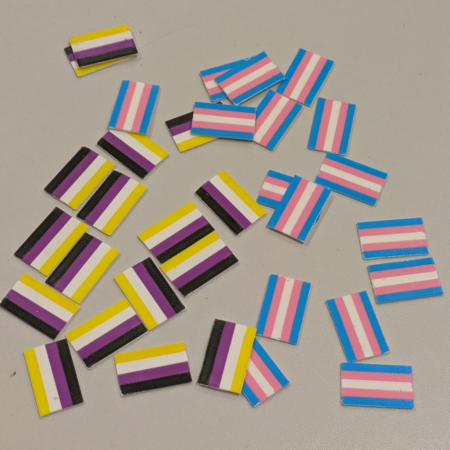 a bunch of plasctic rectangular trans and enby flags scattered on a table